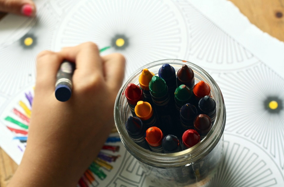 Sie sehen eine Stiftebox sowie die Hand eines malenden Kindes. © Pixabay